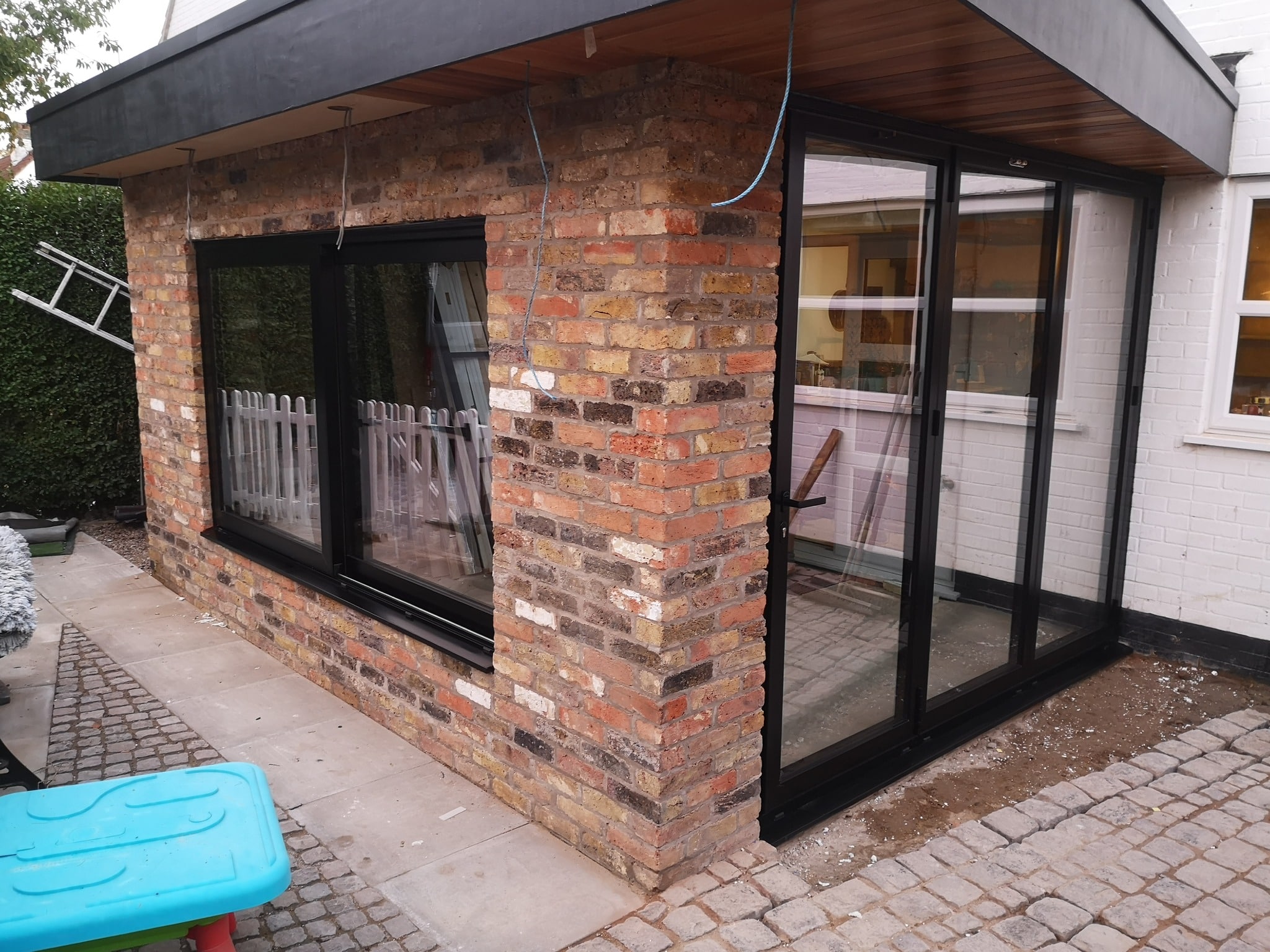 the installation of a 3-panel Schüco bi-folding door, a sliding window, and two fixed picture windows.